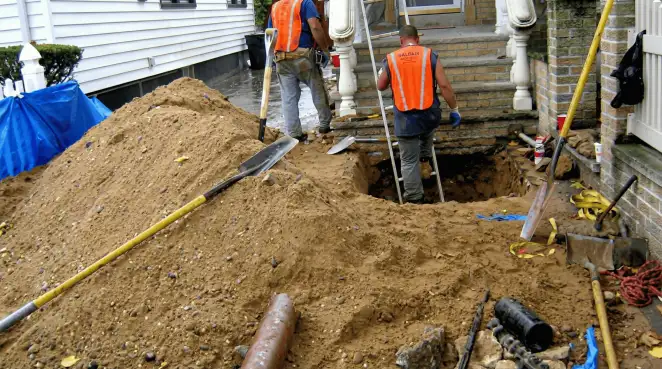 Contractors performing foundation protection and exterior drainage excavation near residential home steps in Chicago, IL